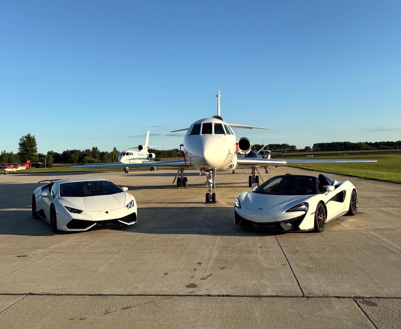 Private jet with exotic cars on the tarmac